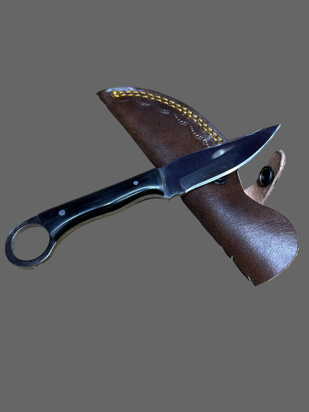 A fixed-blade knife with a black handle and a brown leather sheath, laid on a brown and beige animal fur surface.